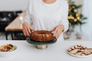 Woman prepares bundt cake for holiday celebration with Christmas decor.